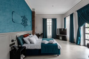 A hotel room with a large bed, a TV, a desk with a chair, and a view of the outdoors. - Richmond Hotel (Chisinau)