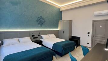 A hotel room with two beds, a desk, a wardrobe, and a wall-mounted air conditioner.
