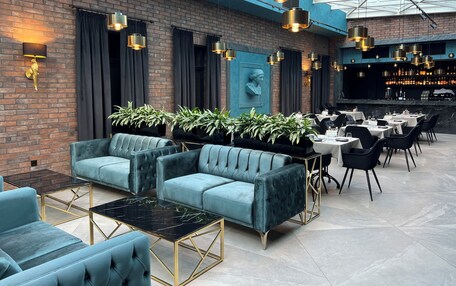 A modern lounge area with plush seating, a bar, and a high ceiling with skylights.