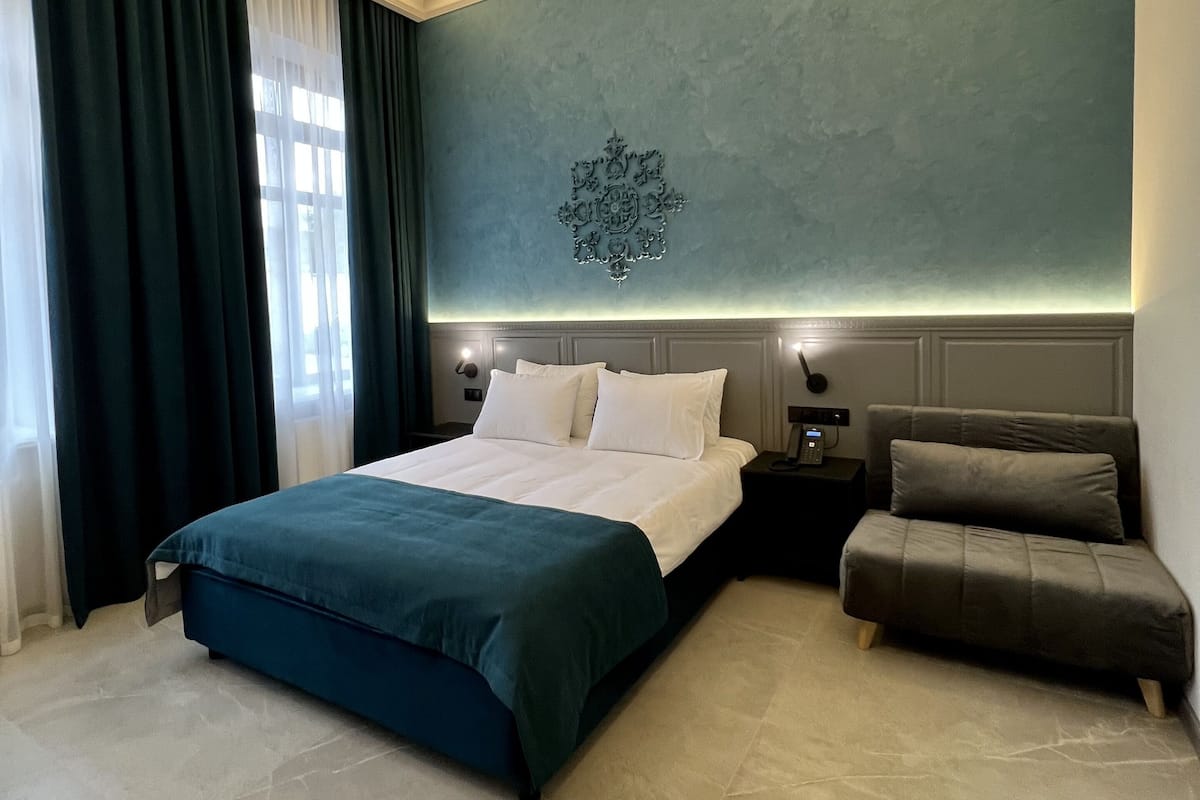 A modern bedroom with a large bed, a bedside table, a nightstand, and a small sofa.
