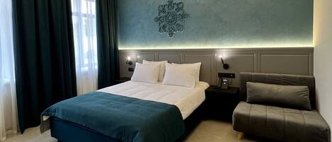 A modern bedroom with a large bed, a bedside table, a nightstand, and a small sofa.
