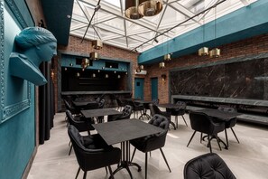 A modern restaurant with black leather chairs, a glass ceiling, and a brick wall. - Richmond Hotel (Chisinau)