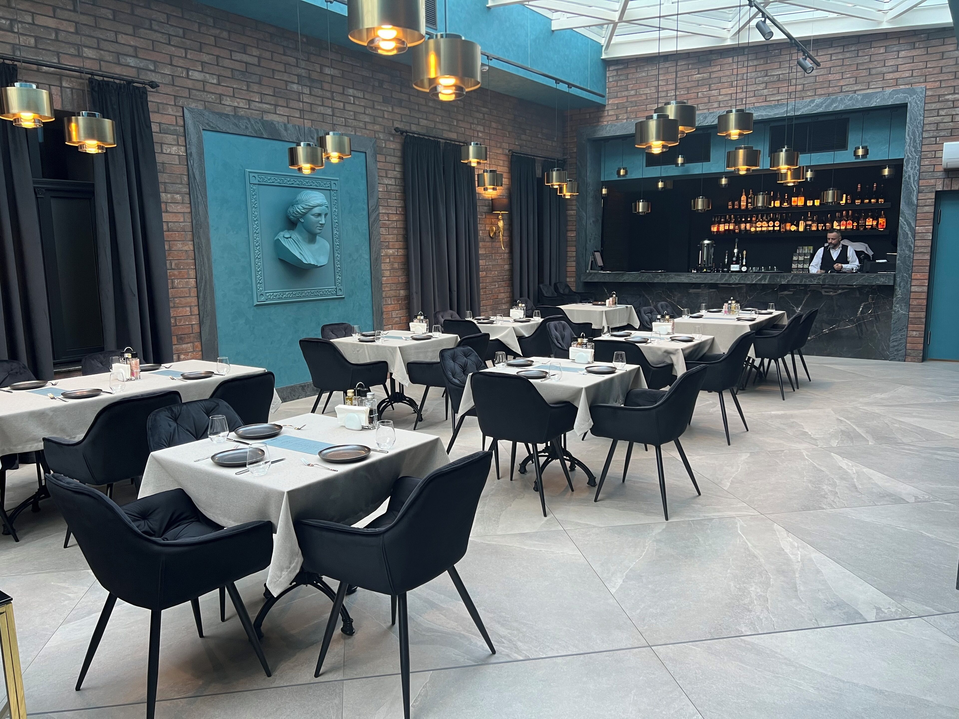 A restaurant with multiple tables and chairs, a bar area, and a mural on the wall.