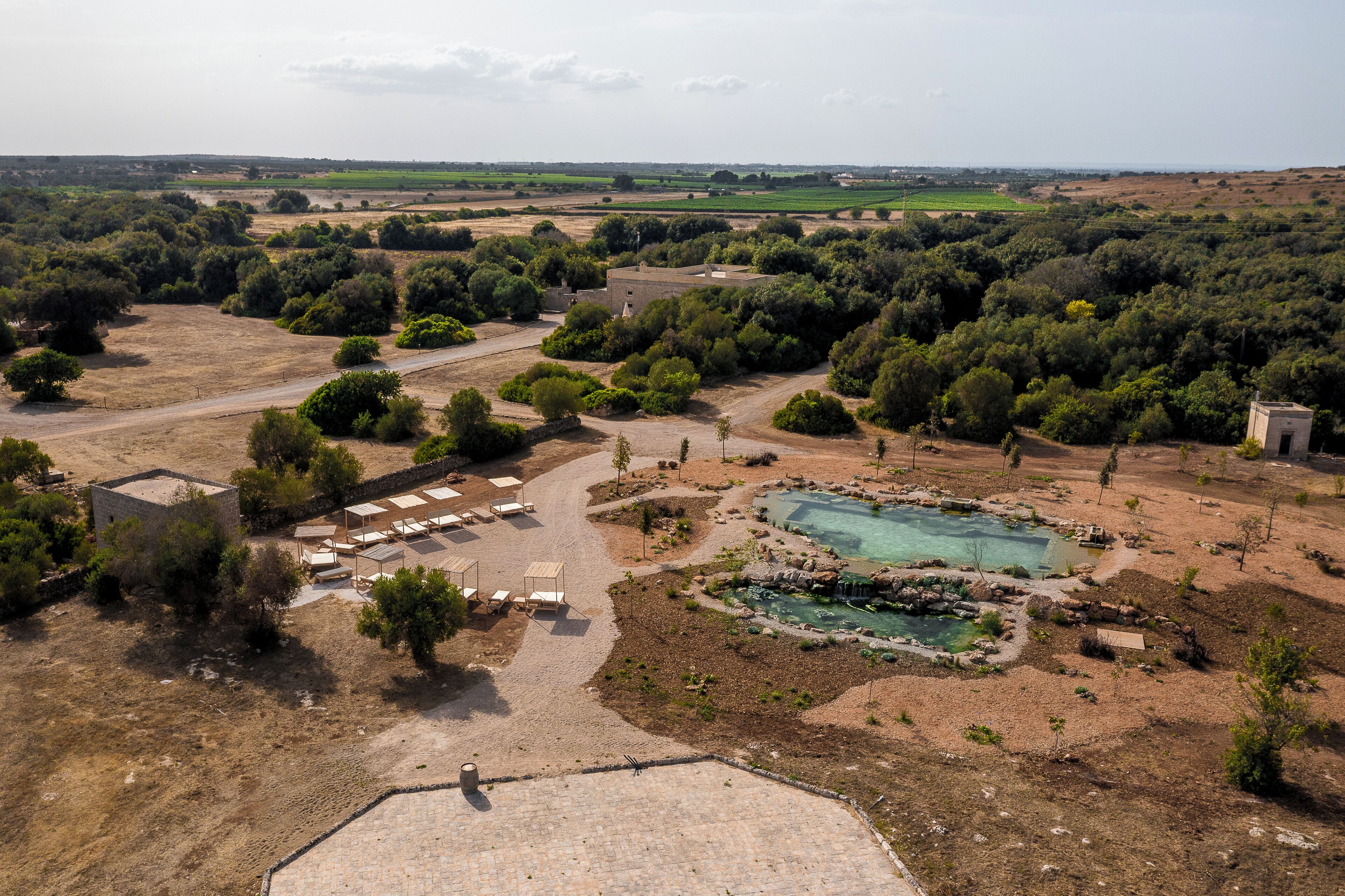 Vue a érienne d’un complexe hôtelier doté d’une piscine, d’un espace de détente et d’une végétation luxuriante.