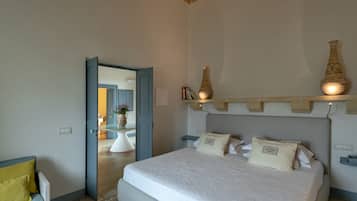 A bedroom with a large bed, a bedside table, a nightstand, and a shelf with decorative items.