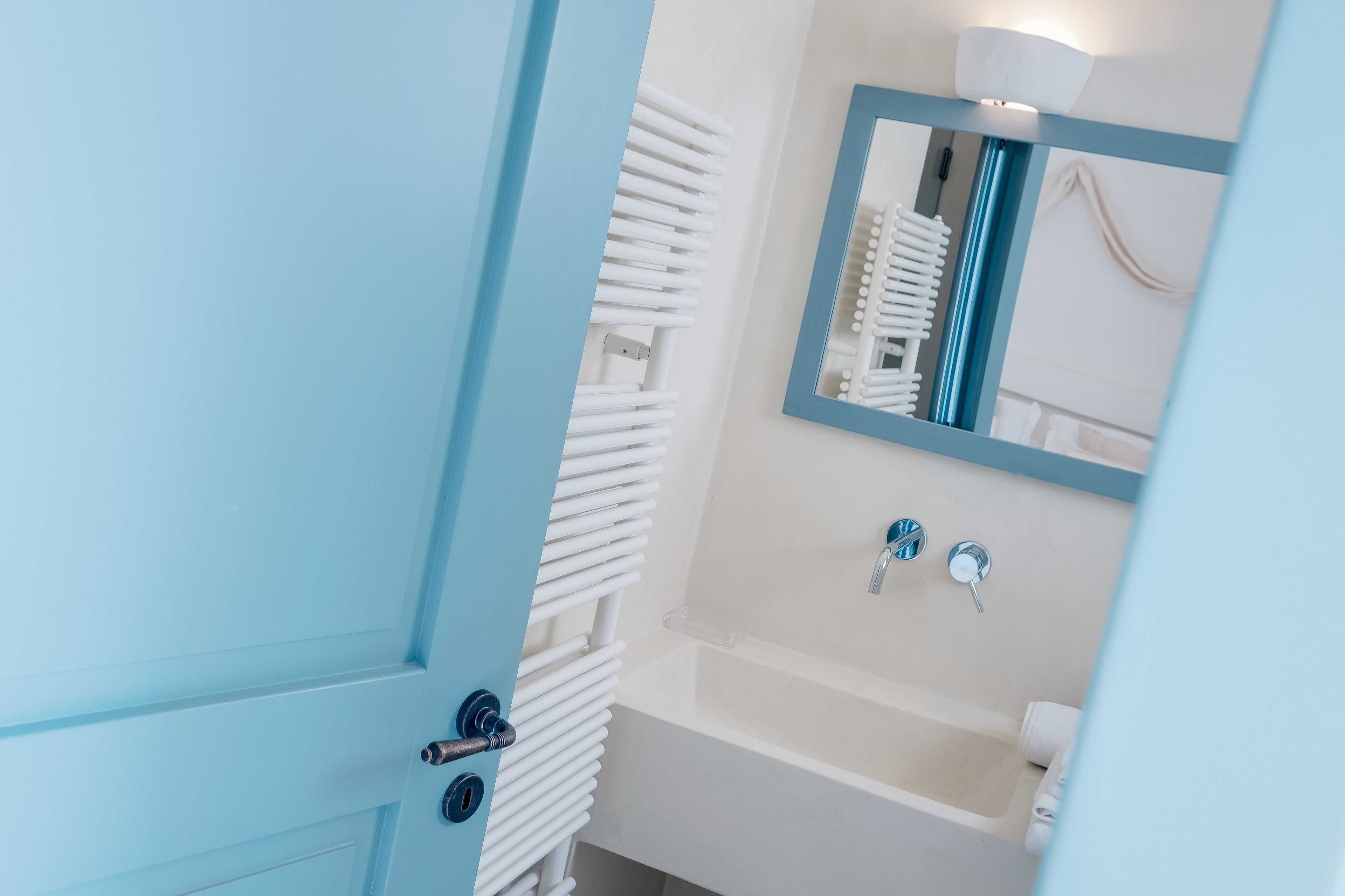 A bathroom with a white bathtub, a mirror, and a towel rack.