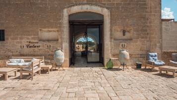 A courtyard with stone paving, a large arched doorway, and outdoor seating with vases.