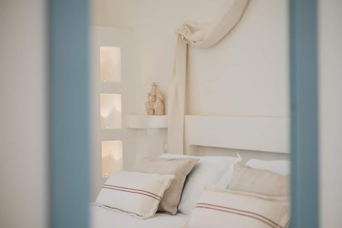 A bedroom with a bed, pillows, a nightstand, and a wall-mounted sculpture.