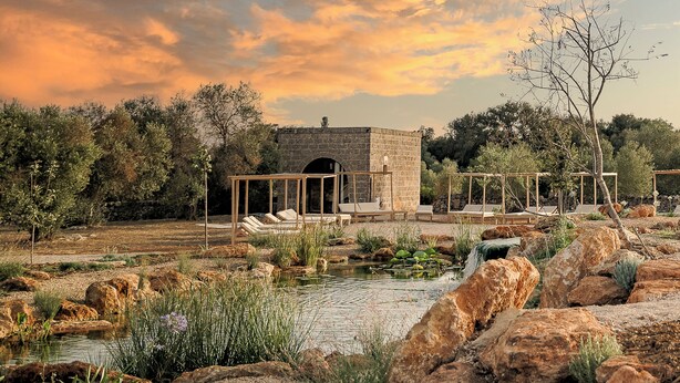 A stone structure with a covered seating area and a small pond. - Masseria Cuturi (Manduria)