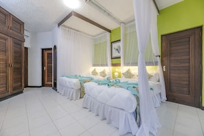 A hotel room with three beds, a large window with curtains, a wooden wardrobe, and a green accent wall. - Safari Beach Hotel  (Diani Beach)