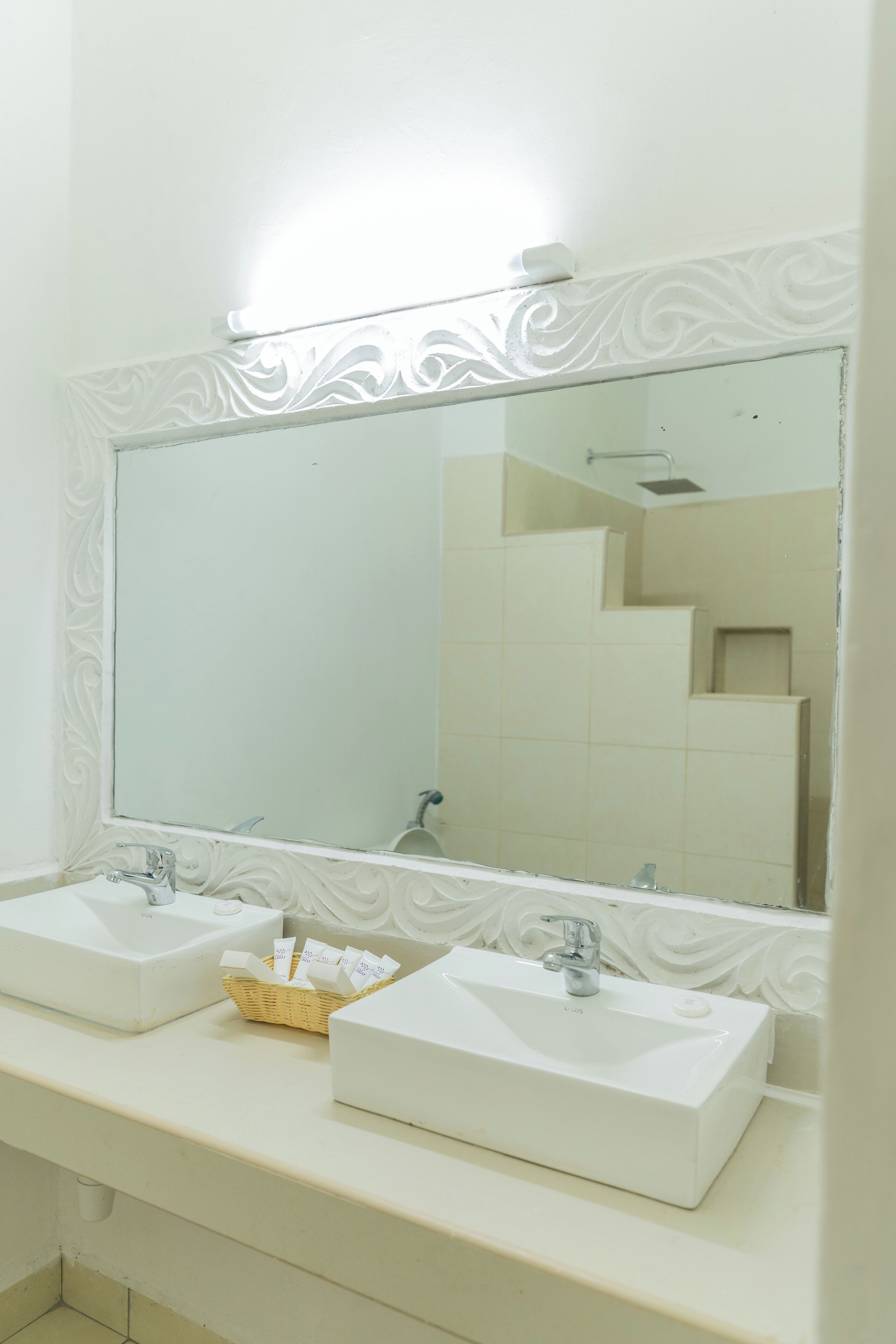Un bagno con due lavabi, uno specchio ampio e un pannello decorativo a parete.