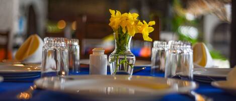 A table set with plates, glasses, and a vase with yellow flowers.