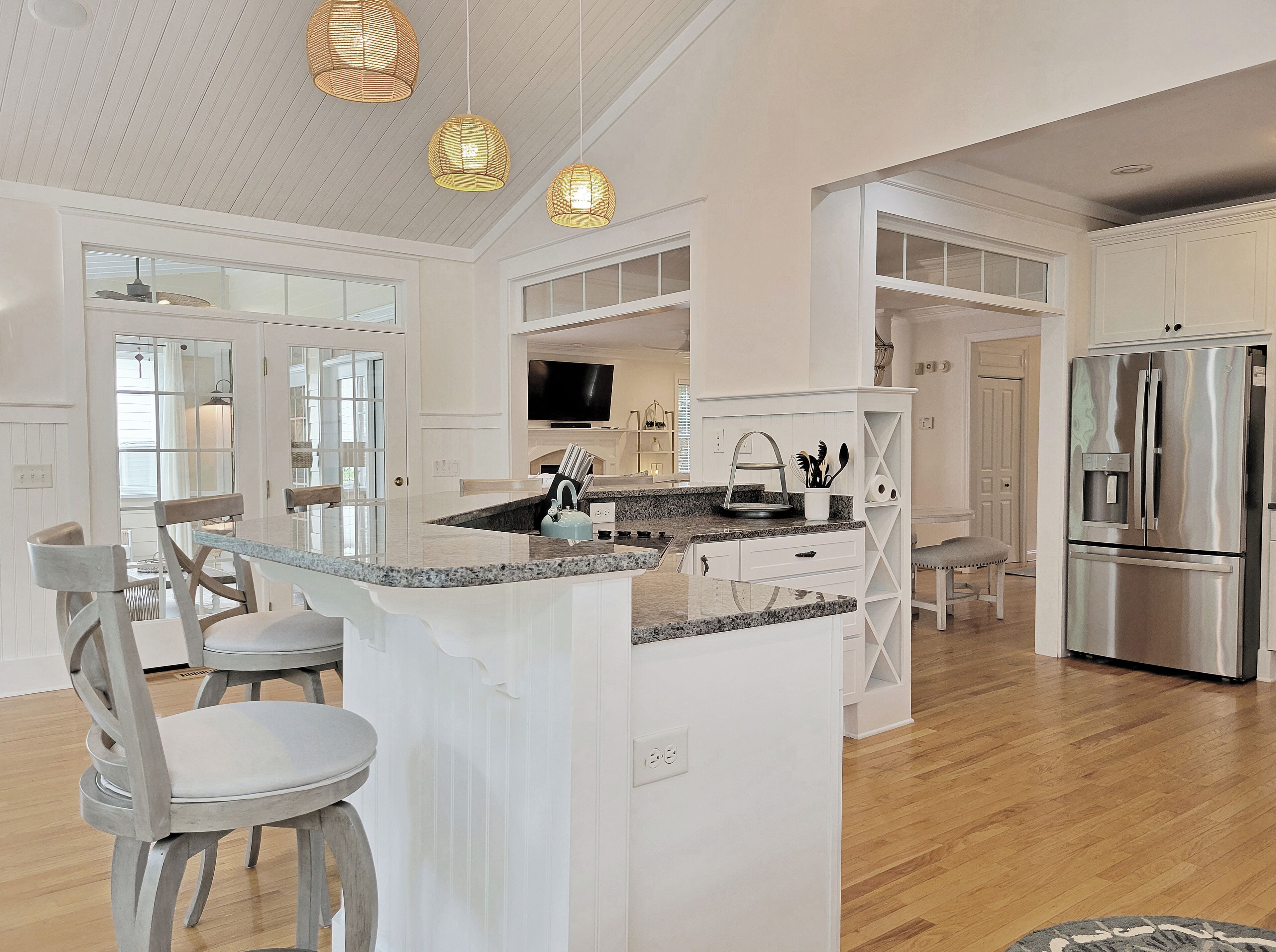 A spacious kitchen with white cabinetry, a central island, and a stainless steel refrigerator.