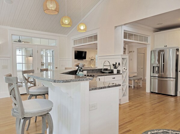 A spacious kitchen with white cabinetry, a central island, and a stainless steel refrigerator.