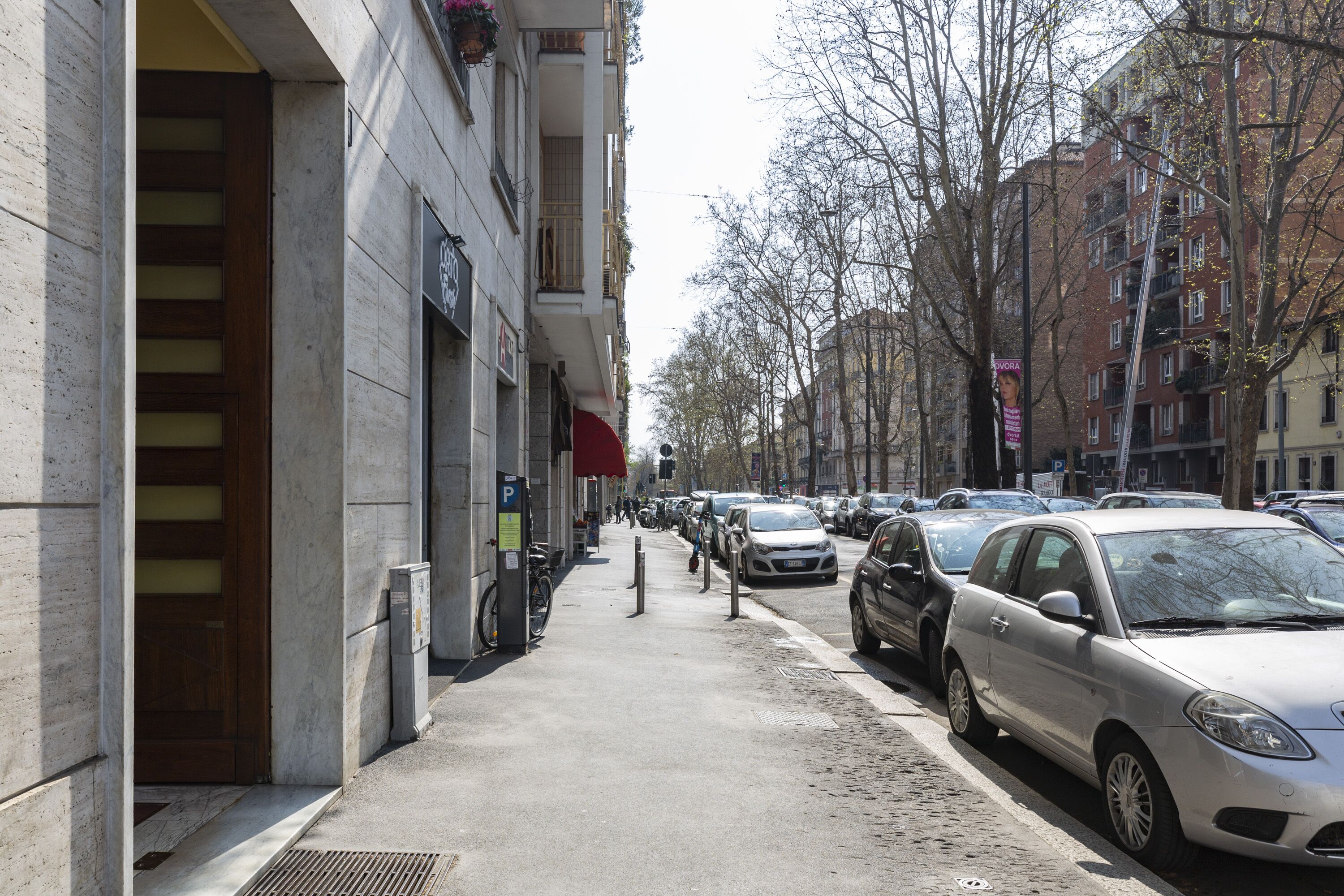 Une rue de la ville avec des voitures garées, un trottoir et des immeubles dotés de balcons.