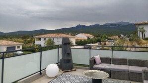 A balcony with a wicker sofa, a round table, and a large white spherical object. - Villa Moderne Proche Solenzara (Ventiseri)