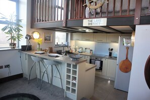 A modern kitchen with a bar area, a dining table set for two, and a sign indicating 'The Lake District'. - The Dairy at Brackenthwaite Farm (Carnforth)
