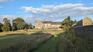 A stone building with multiple windows and a grassy field in front. - The Dairy at Brackenthwaite Farm (Carnforth)