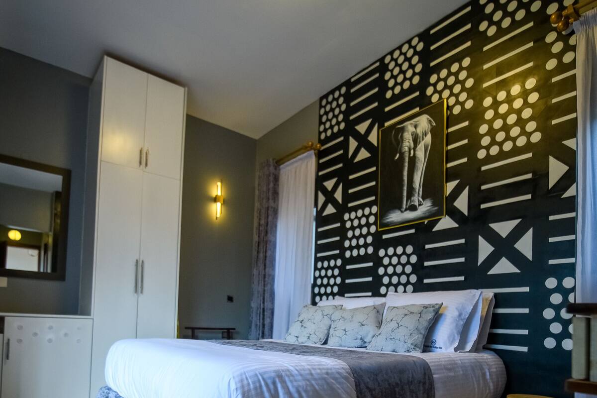 Quarto com cama, guarda-roupa e parede com padrão geométrico.
