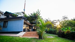 A modern house with a balcony, a small garden, and a staircase leading to the entrance. - Pangolin Nest Boutique Hotel (Kampala)