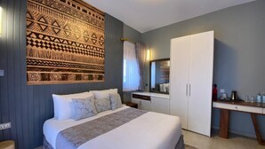 A bedroom with a large bed, a wardrobe, a desk, and a patterned wall. - Pangolin Nest Boutique Hotel (Kampala)