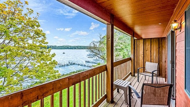 Une terrasse en bois offrant une vue sur un lac et des collines lointaines.