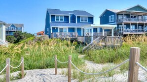 A beachfront property with a large house featuring a balcony and a covered porch. - Enjoy a spacious oceanfront duplex at Codfather Unit 2 (Oak Island)