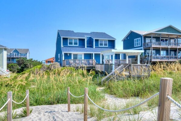 A beachfront property with a large house featuring a balcony and a covered porch.