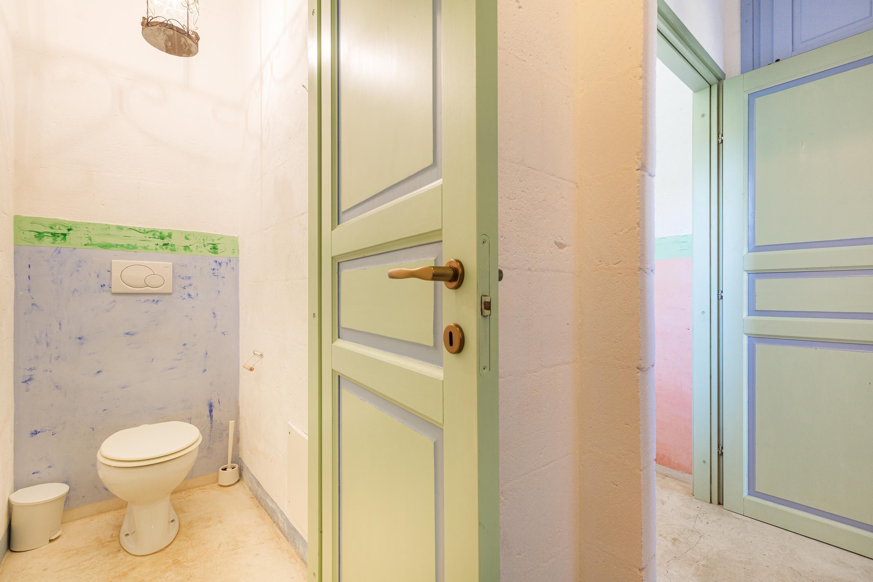 A bathroom with a toilet, a green door, and a white wall.