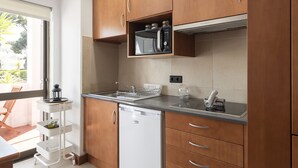 A compact kitchen with wooden cabinets, a built-in microwave, a dishwasher, and a small countertop. - Alvaflor 102 - Vilamoura by HD Properties (Vilamoura)