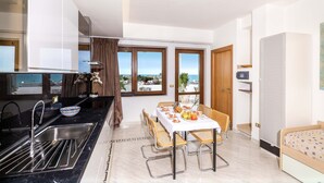 A modern kitchen with a sink, a dining table set for two, and a view of the sea through large windows. - 3365 A Casa di Anna - Ilaria by Barbarhouse (Vieste)