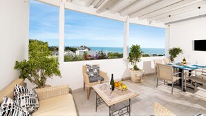 A sunlit patio with a view of the sea, wicker furniture, a table with wine glasses, and potted plants. - 3365 A Casa di Anna - Ilaria by Barbarhouse (Vieste)