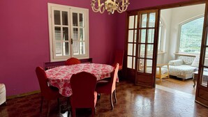 A dining area with a table set for four, a chandelier, and a view of a bed through a glass door. - Large apartment with pool and garden, ideal for families, 10 km from the sea. (Sarola)