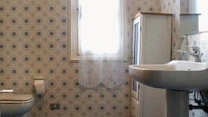 A bathroom with a toilet, a sink, and a window with a curtain. - Large apartment with pool and garden, ideal for families, 10 km from the sea. (Sarola)