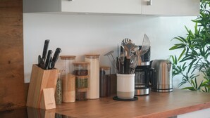 Una encimera de cocina con diversos utensilios, frascos y una cafetera.