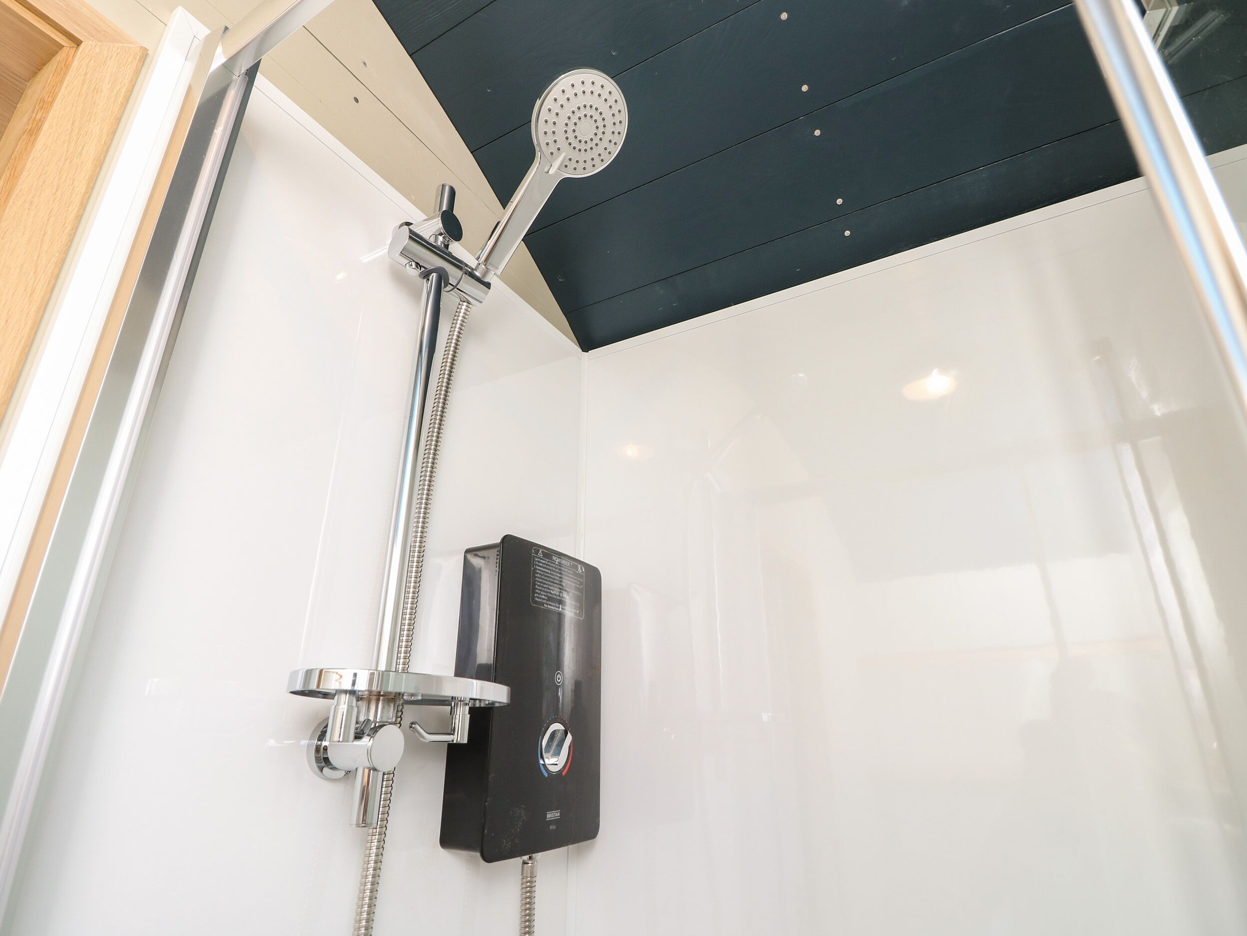 Een moderne douche met een handdouche en een bedieningspaneel aan de muur.
