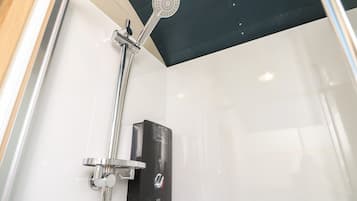 Ducha moderna con cabezal de ducha de mano y panel de control en la pared.