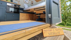 Una habitación compacta y moderna con literas, cocina integrada y un pequeño comedor.
