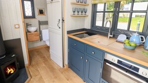 Cocina moderna con armarios de madera, horno empotrado y ventana con vistas al exterior.
