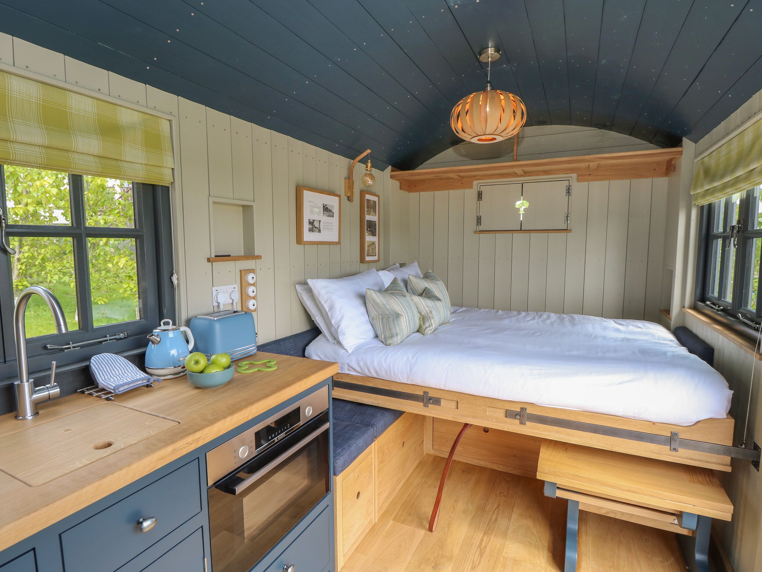 Un dormitorio pequeño con cama, mesita de noche y un banco de madera empotrado.