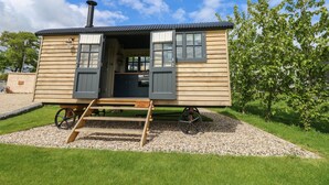A wooden mobile home with a kitchen area, a chimney, and a small porch. - Malbec (Ryde)