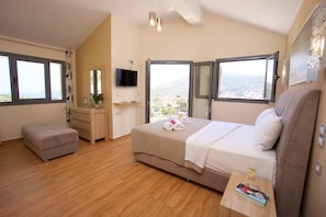 Relax in this serene bedroom with a large bed, dresser, and TV, offering a view of the surrounding landscape.