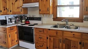 Una cocina con armarios de madera, estufa, fregadero y ventana.