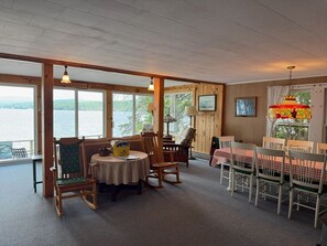 A dining area with a view of the water, wooden walls, and a table with chairs. - Lake and Mountain views! (Sanbornton)