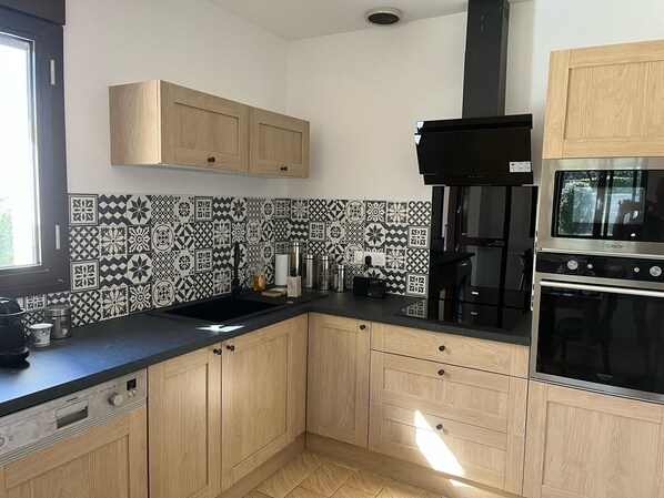 A modern kitchen with wooden cabinets, a black countertop, and a patterned backsplash.