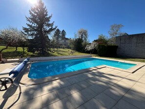 A rectangular swimming pool with a clear blue water surface, surrounded by a tiled deck.