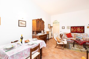 A dining area with a table set for two, a wooden cabinet, and a sofa with patterned cushions. - 3363 Casa Giovanna by Barbarhouse (Ischitella)