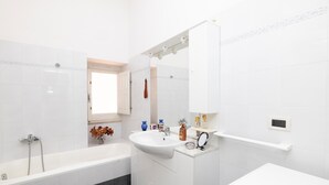 A modern bathroom with a bathtub, a sink, and a mirror. - 3363 Casa Giovanna by Barbarhouse (Ischitella)