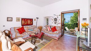 A living room with two patterned sofas, a coffee table, and a dining area with chairs. - 3363 Casa Giovanna by Barbarhouse (Ischitella)