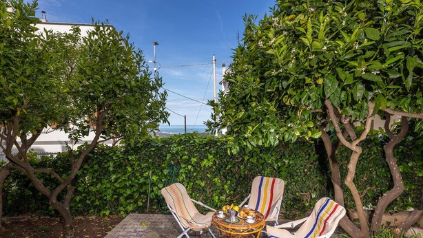 A patio with a wicker table, striped chairs, and potted plants. - 3363 Casa Giovanna by Barbarhouse (Ischitella)